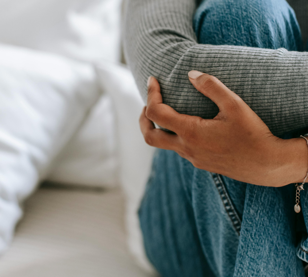 woman sitting alone holding her legs worried about unplanned pregnancy