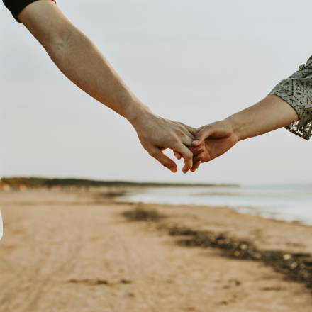 A couple gently holding hands, offering each other comfort and support. Their hands rest on a bench, symbolizing togetherness during a difficult time, such as coping with pregnancy loss.