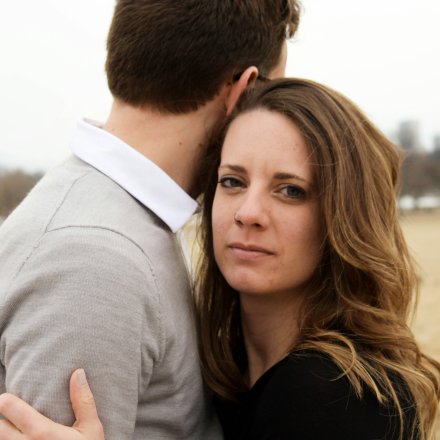 couple hugging, woman looking serious